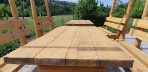 a wooden picnic table with two wooden chairs at Camping Pentru Rulote, Auto Rulote, Corturi Personale La Barbosu in Lepsa, Vrancea in Lepşa