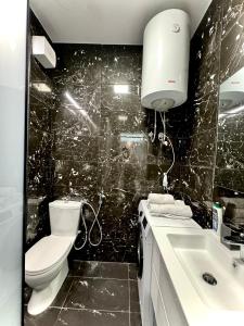 La salle de bains est pourvue de carrelage noir, de toilettes et d'un lavabo. dans l'établissement Seaside Beach Apartments - by EKA Luxury Apartments, à Durrës