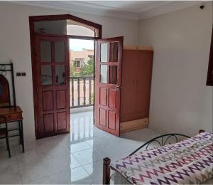 a bedroom with a door and a bed and a balcony at Villa Française à Dallas Saidia in Saidia 
