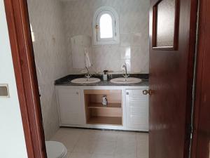 a bathroom with two sinks and a mirror at Villa Française à Dallas Saidia in Saidia 