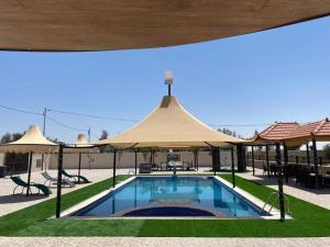 a swimming pool with a large umbrella over it at شاليهات ومسابح مزارع in Al Azraq ash Shamālī