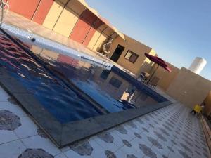 a swimming pool in front of a house with a building at شاليهات ومسابح مزارع in Al Azraq ash Shamālī
