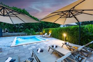 un patio con 2 sombrillas y una piscina en Apartment Mara by EL-PI TOURS, en Malinska