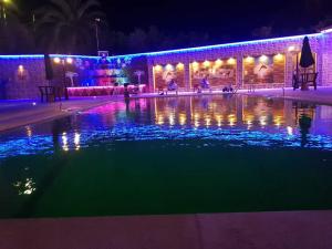 a swimming pool lit up at night with lights at شاليهات ومسابح مزارع in Al Azraq ash Shamālī