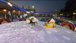 a table with a vase of flowers on top at شاليهات ومسابح مزارع in Al Azraq ash Shamālī
