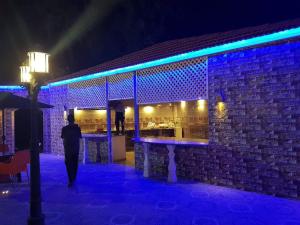 a man walking past a bar at night at شاليهات ومسابح مزارع in Al Azraq ash Shamālī
