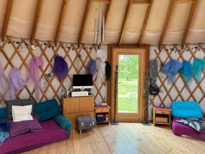 Una habitación con un sofá y una ventana en una yurta. en Eco-lodge Ecoute la Vie, en Lunay