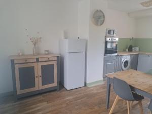 a kitchen with a white refrigerator and a wooden table at La Mancelliere in Isigny-le-Buat