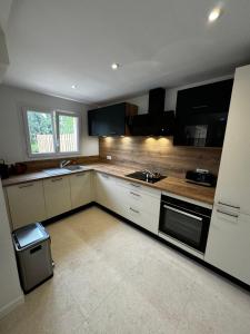 a kitchen with white cabinets and black appliances at T3 avec jardin - mer, soleil et tout à pied in Cavalaire-sur-Mer +5 photos