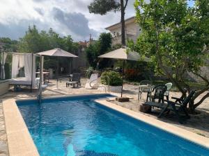 a pool with chairs and umbrellas next to a house at Villa Maria Mercedes in Olesa de Bonesvalls