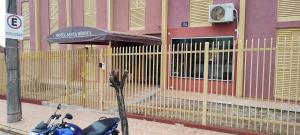 uma moto estacionada em frente a uma cerca em Hotel Sta Mônica Marília em Marília