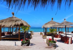 a pathway on the beach with umbrellas and the ocean at At Konan's in Vlorë