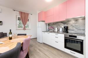 cocina con armarios rosas y mesa de madera en Apartment Mara by EL-PI TOURS, en Malinska