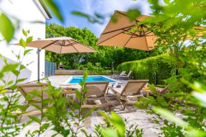 Un patio con mesa, sillas y sombrillas. en Apartment Mara by EL-PI TOURS, en Malinska