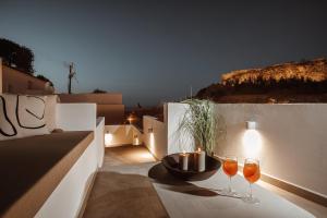 two wine glasses sitting on a table on a balcony at Noema Lindos - Athena Apartment in Lindos