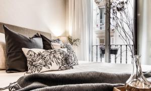a bed with black and white pillows and a window at Soul Apartmet in Pamplona