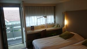 una camera da letto con un letto, una scrivania e una finestra di Campanile Bayonne a Bayonne Altre 26 foto