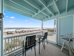 a balcony with chairs and a table and a view of the ocean at Beach Bliss condo in Carolina Beach