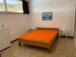 a bedroom with a bed with an orange blanket at Appartamento in residence con piscina in Marina di Bibbona +51 photos
