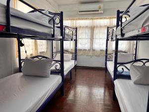 a room with three bunk beds in a room at Yuma Tashi Hostel in Bangkok
