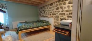 a bedroom with a bed and a sink and a stone wall at Le Mazel in Saint-Agrève