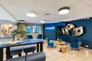 a waiting room with blue walls and blue chairs at La Closerie SPA & Résidence Hôtel in Deauville