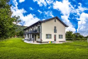 a large white house with a green yard at Transalpina Retreat in Novaci