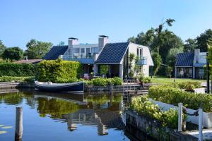 a house and a boat on a river at Amsterdam / Loosdrecht Rien van den Broeke Village in Loosdrecht