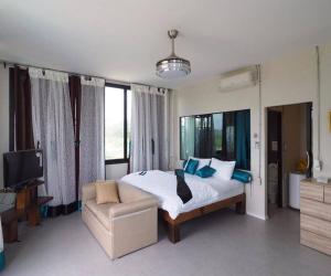 a bedroom with a bed and a couch and a tv at Daiya Nirvana Pool Villa, Khao Yai in Klang Dong +98 photos