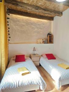 a bedroom with two beds with red pillows at Maison de village avec jardin clos in Bouzic