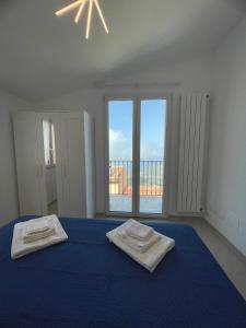 een slaapkamer met een blauw bed met 2 handdoeken erop bij Pollina Suites & Apartments in Pollina