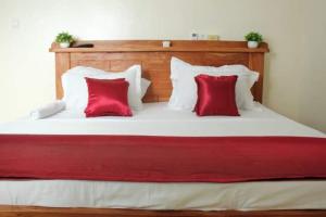 a large bed with two red pillows on it at Résidences Hôtel Perle Bleue in Cotonou