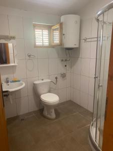 a white bathroom with a toilet and a sink at green olive 2 in Budva