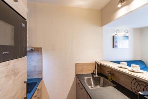 a small kitchen with a sink and a counter at La Closerie SPA & Résidence Hôtel in Deauville