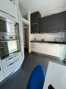 a kitchen with white cabinets and a blue chair at M&M BERGAMO CENTER - Modern flat with FREE WIFI - Rent BIKE in Bergamo