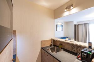 a bathroom with a sink and a mirror at La Closerie SPA & Résidence Hôtel in Deauville