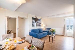 a living room with a blue couch and a table at La Closerie SPA & Résidence Hôtel in Deauville