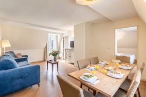 a living room with a table and a blue couch at La Closerie SPA & Résidence Hôtel in Deauville