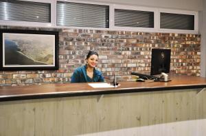 a woman sitting at a counter in front of a brick wall at Swakopmund Plaza Hotel in Swakopmund
