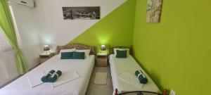 two beds in a room with green walls at VuBra in Ulcinj
