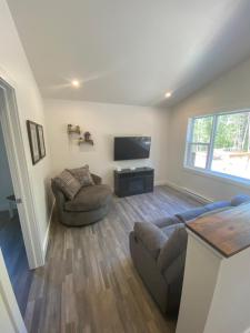 a living room with a couch and a flat screen tv at The Hideaway Cottage with Private trails in Waweig