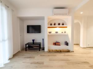 a living room with a table and a tv on a wall at Solar dos Pinheiros in Vilamoura