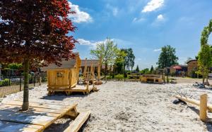 a playground with a wooden house in the sand at Nieuw!! Chalet De Luxe 4 persoons met airco in Oorsbeek