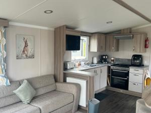 Una sala de estar con un sofá y una cocina. en Robinson retreats beautiful caravan with sea views pet friendly, en Mainsriddle