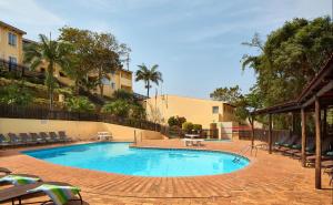 a swimming pool in a courtyard with chairs and trees at Ballito Beachfront Resort - 34 Chaka Chalets in Ballito