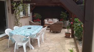 eine Terrasse mit einem Tisch, Stühlen und einem Sofa in der Unterkunft Charmante maison dans village in Champcueil