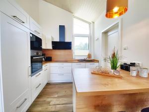a kitchen with white cabinets and a wooden counter top at Seeschwalbe 329 in Mirow +6 photos