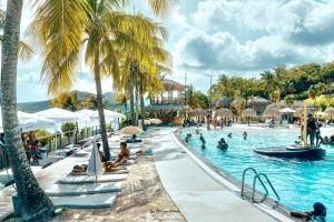 a group of people in a swimming pool with palm trees at Ti studio coquet vue mer 180 degrés face Diamant, piscine de standing in Le Diamant