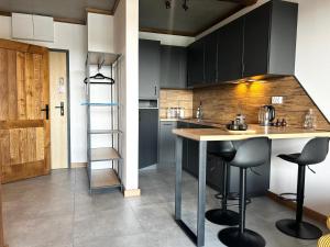 a kitchen with black cabinets and a island with bar stools at Loft House klimatyzowany Apartament - Jezioro Nyskie, Nysa in Nysa