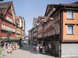 un gruppo di persone che camminano per una strada con edifici di Hotel Löwen ad Appenzello